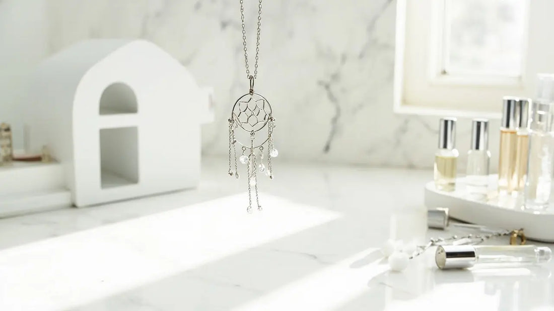 minimalist flat lay of jewelry, perfume rollers, and tabletop fireplace on marble